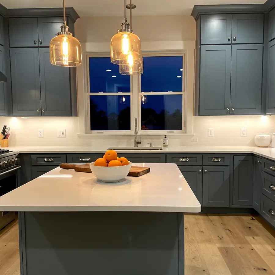Blue-grey kitchen cabinets under evening pendants