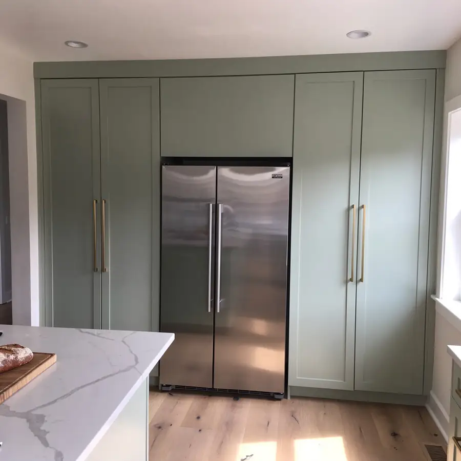 Pale sage pantry cabinets flanking refrigerator